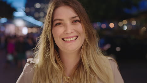 retrato en primer plano de una hermosa mujer rubia sonriendo feliz ante la cámara disfrutando de una hermosa noche urbana