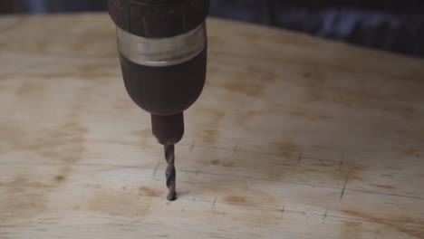 a person using an electric drill to bore a hole in a piece of plywood