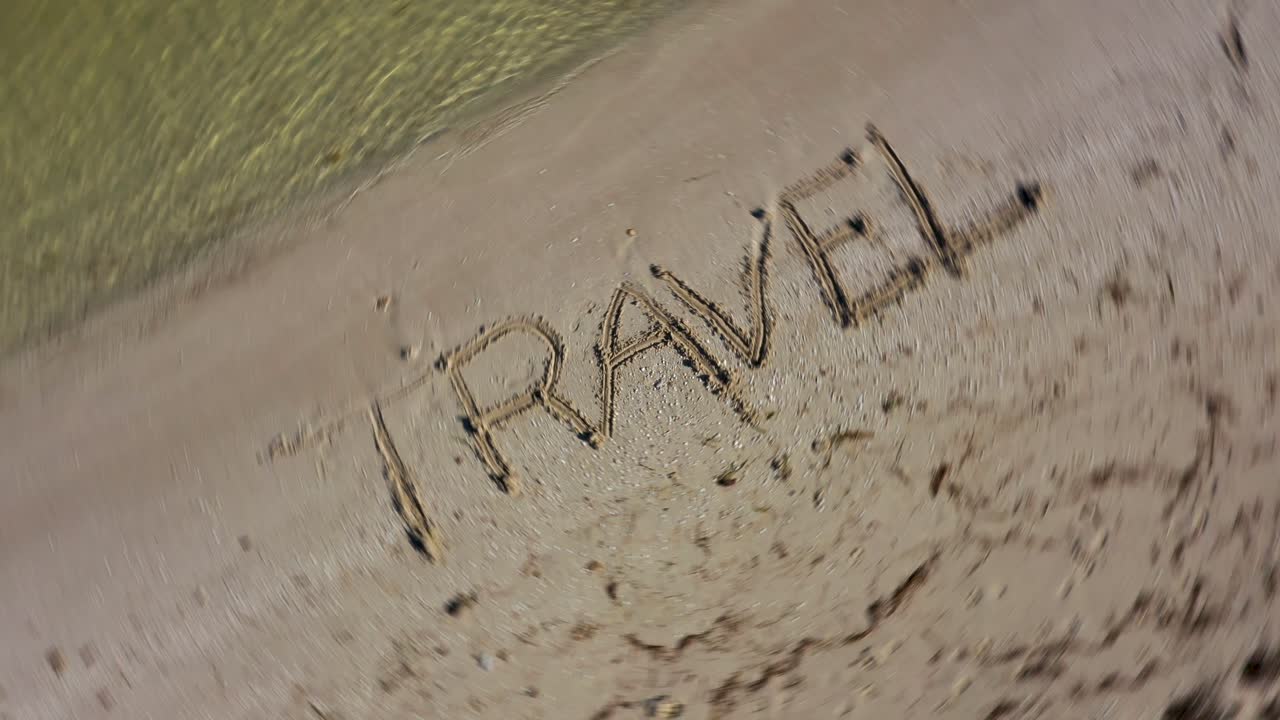 viaje escrito en la arena y girando en el sentido de las agujas del reloj