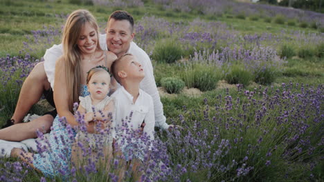 portrait of a happy family with two children sitting on a blooming lavender field