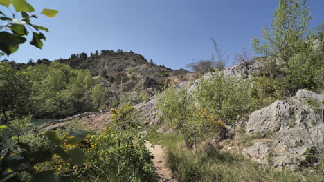 path in between trees and rocky mountains along a river france sunny day