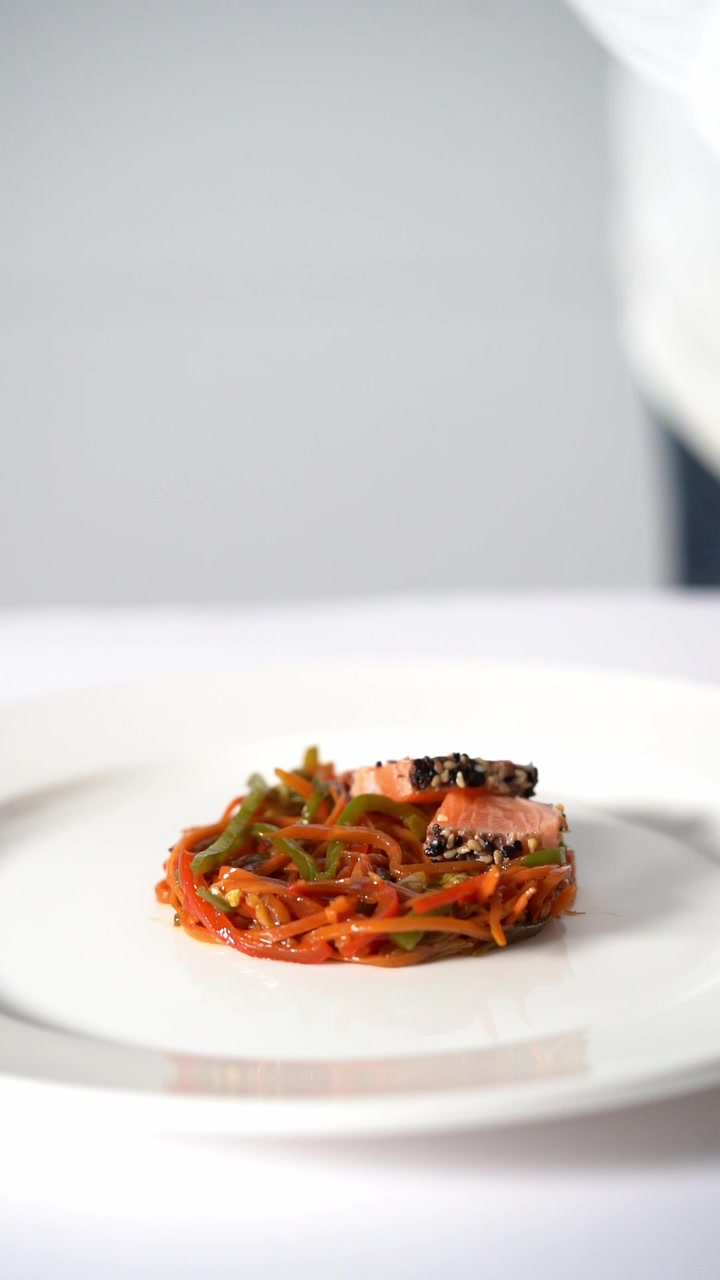 Chief plating a gourmet dish with vegetables and meat in a minimalist style, close up shot, insert shot
