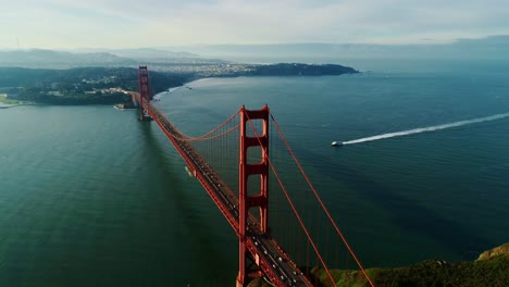 early morning boat travels beneath san francisco’s glowing golden gate bridge