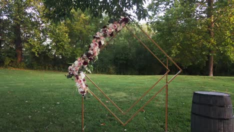 dolly en el tiro de un arco de boda de diamantes con flores y barril en un parque