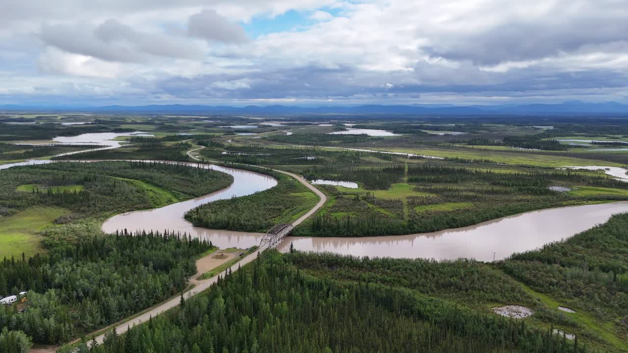 Experience the vast Alaskan wilderness with winding riverways cutting through lush forests, creating a dynamic landscape perfect for travel and adventure videos