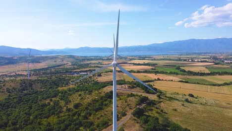 aerial crane shot of wind turbines turning in doirani kilkis greece, lake in background