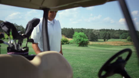 luxury golf sportsman walking to golfing car. rich guy sit cart at country club.