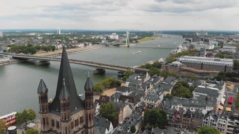 4k footage flying over the historical great saint martin church towards the deutz suspension bridge spanning over the rhine river in cologne, germany