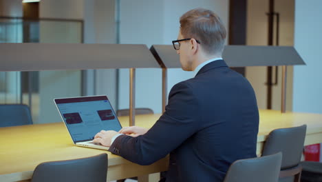 focused businessman working using laptop computer in office - rear view