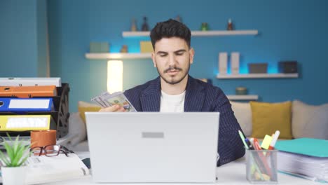 hombre con dinero en la mano mira la computadora portátil y calcula.