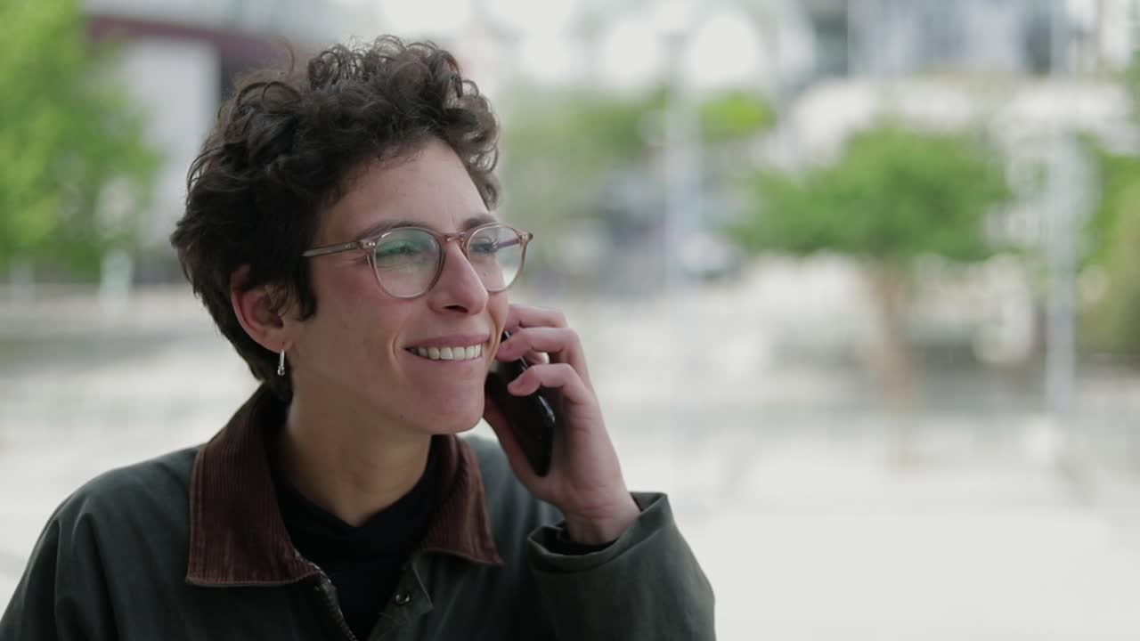 mujer feliz con gafas hablando por teléfono celular al aire libre