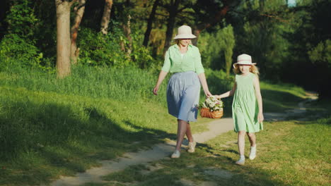 Mutter-Und-Tochter-Gehen-Einen-Waldweg-Entlang-Und-Tragen-Einen-Korb-Mit-Wildblumen