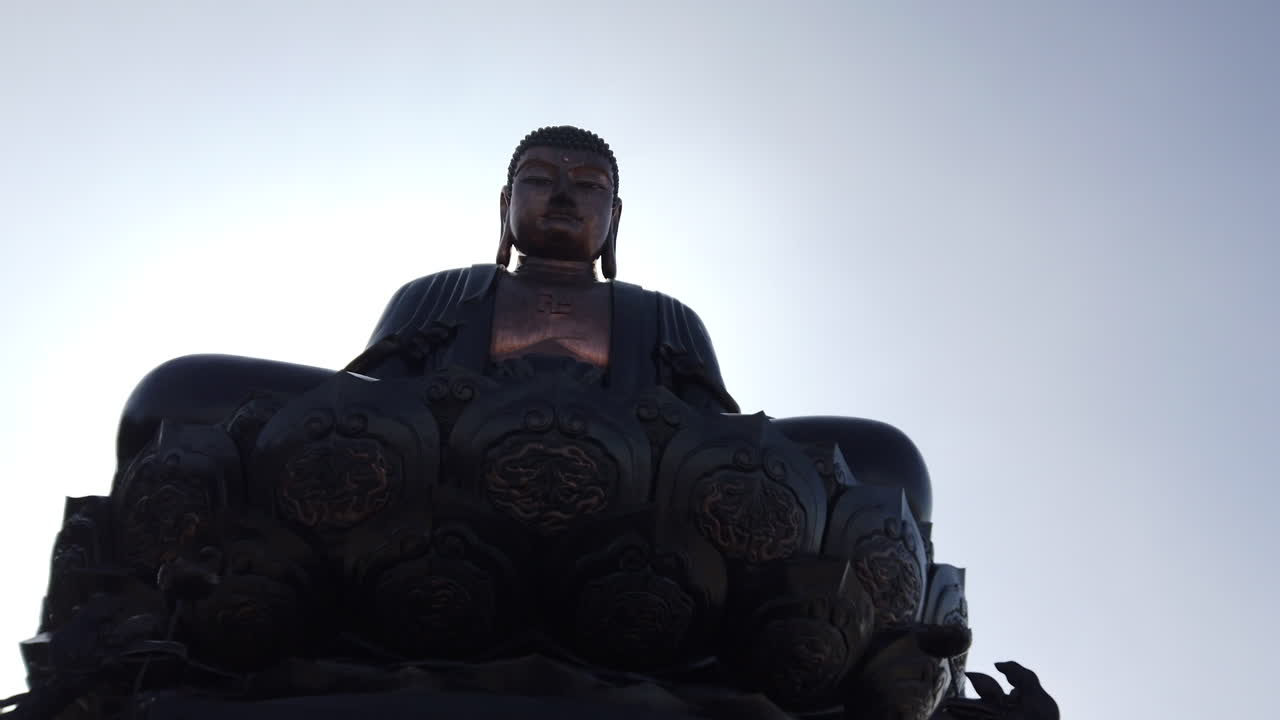 different Panning shot around massive Buddha, pan ends in sunlight hitting lens, backlit, gimbal