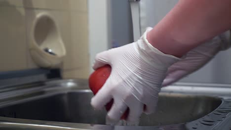 Red-paprika-is-washed-under-running-water-with-disposable-gloves