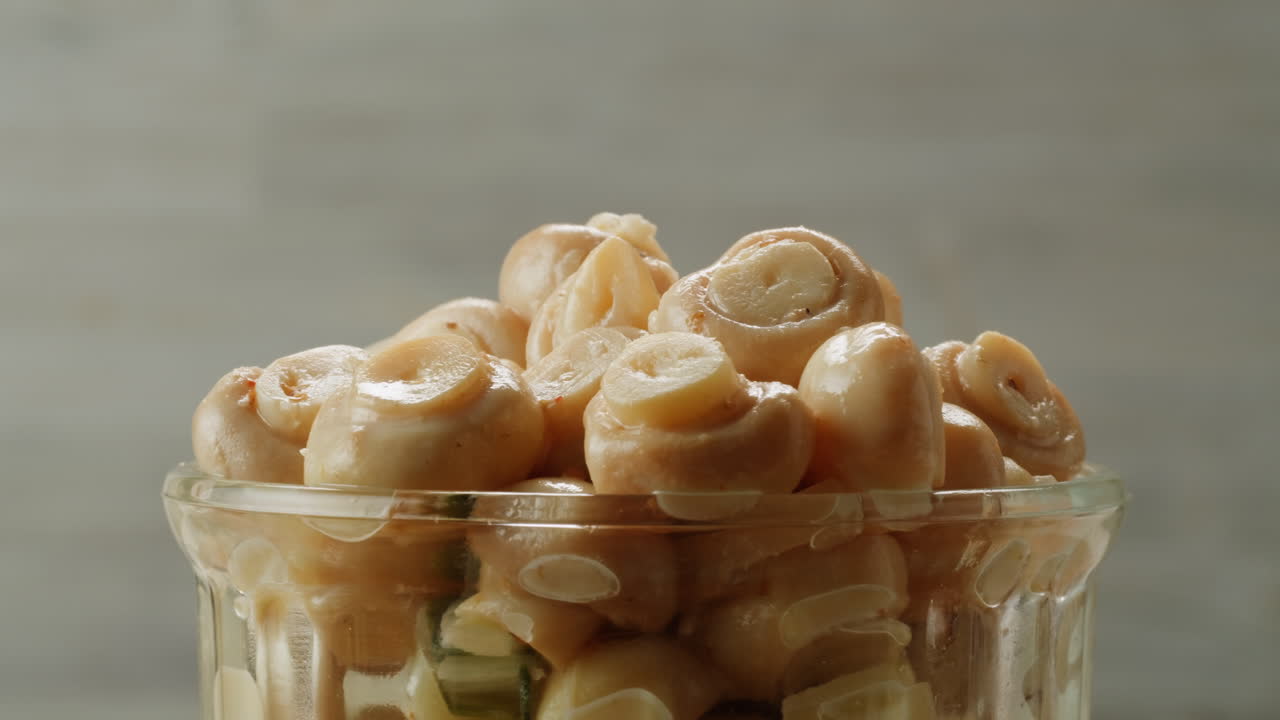 Fermented champignons, Jar with marinated mushrooms on wooden table, traditional salted marinated asian food.