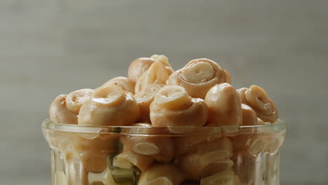 fermented champignons, jar with marinated mushrooms on wooden table, traditional salted marinated asian food.