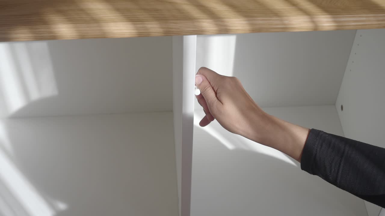 Person opening a white cabinet drawer