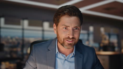 closeup happy businessman videocalling night windows workplace. man waving hand