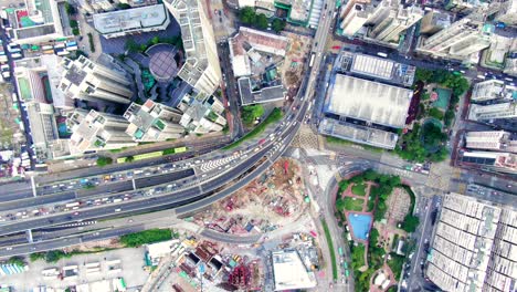 traffic passing through a car park building in downtown hong kong, with city mega buildings, aerial view