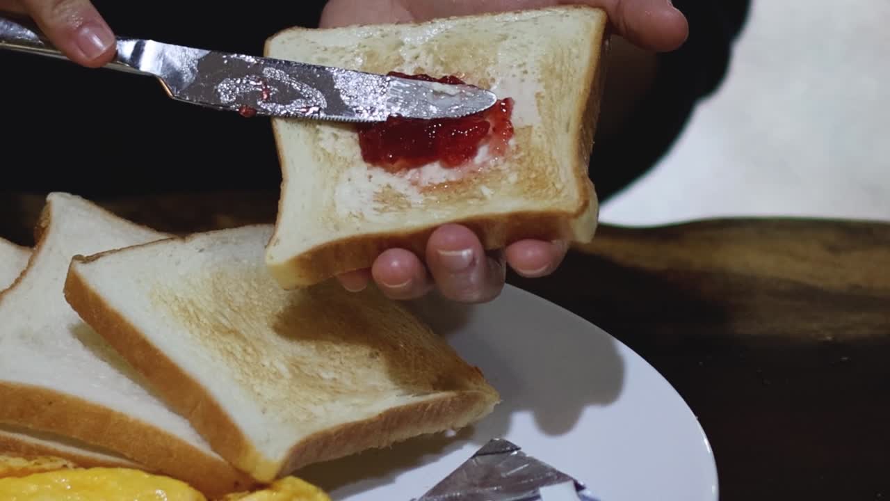 A sequence showing jam being spread on a slice of toast using a knife.