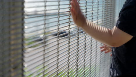 a kid runs his hands along a metal fence