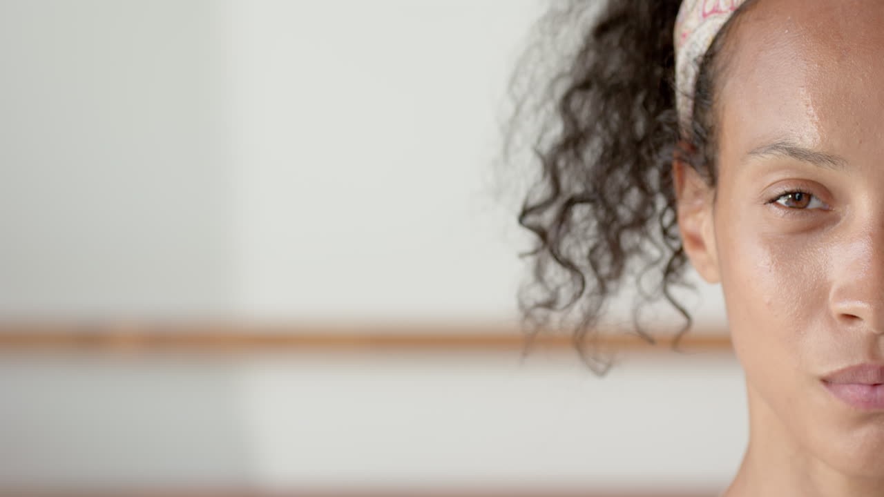 Smiling woman with curly hair wearing headband, standing in bright room, at home, copy space