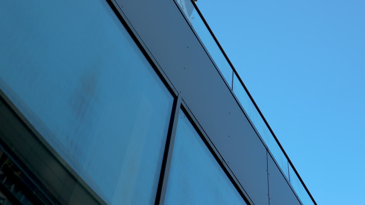 Close-up of modern building's glass facade against blue sky