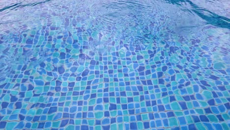 Water-ripples-on-blue-tiled-swimming-pool-during-rain