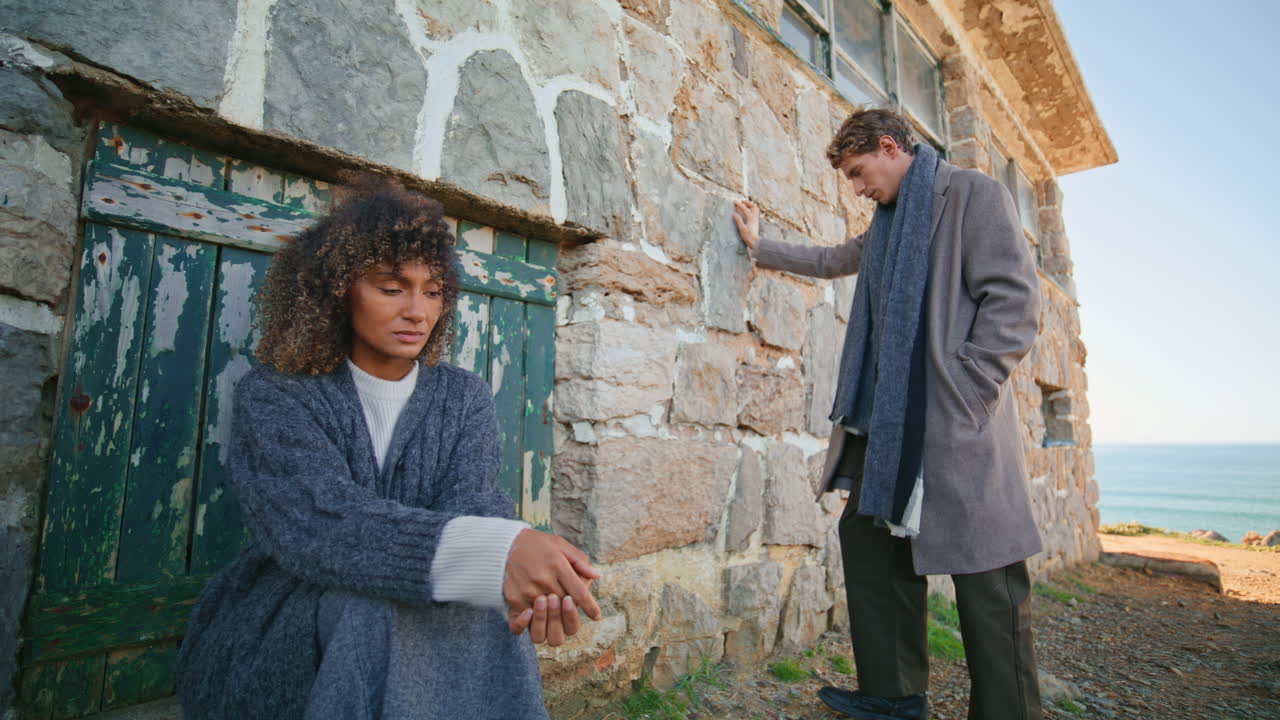 Sad couple posing rocky building. Curly woman blonde man ignoring each other