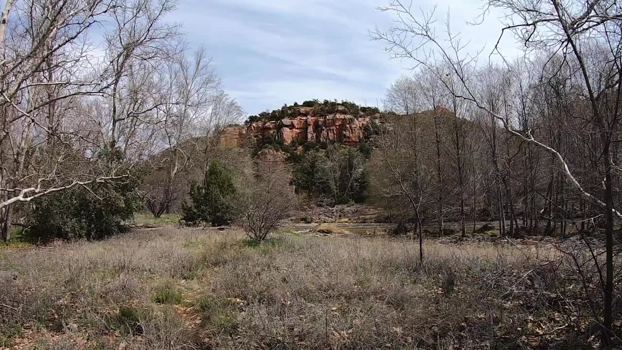 Pan across an open field with a view of the famous red rock formations of Sedona, Arizona