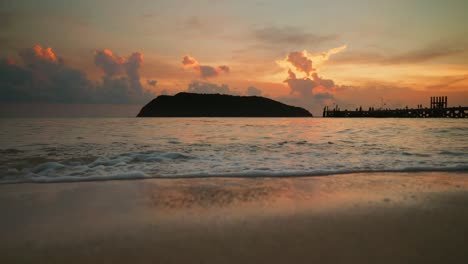 Olas-Del-Océano-En-La-Playa-Contra-La-Isla-Y-El-Muelle-Durante-La-Puesta-De-Sol-En-Cámara-Lenta