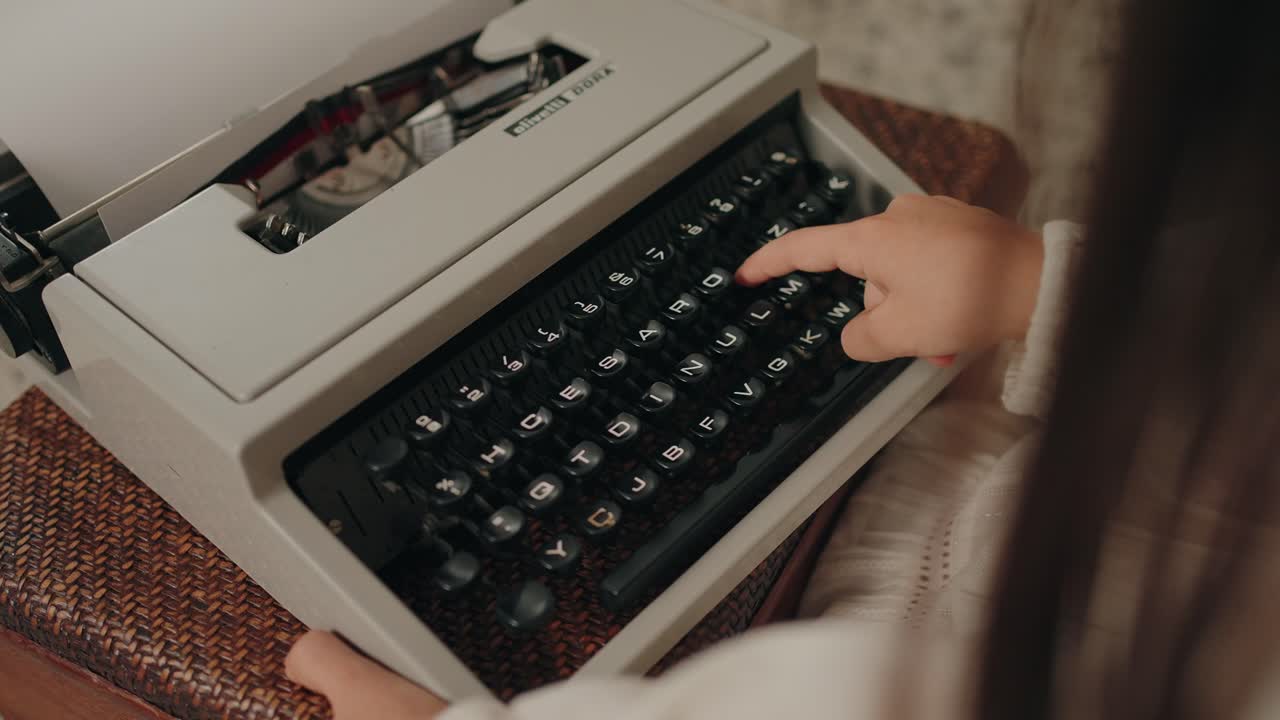 Child typing on a retro typewriter, showcasing hands and black keys in detail