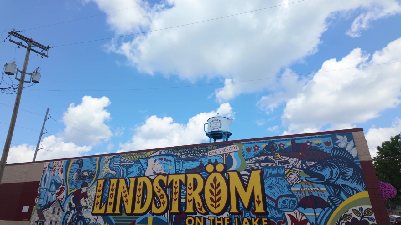 Ampia ripresa in picchiata con gimbal della torre dell'acqua a forma di caffettiera svedese e del murale turistico a Lindström, Minnesota. 4K.
