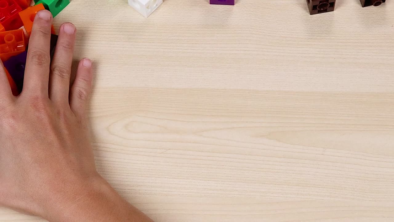 Hands move and organize colorful cubes on a light wooden surface, showcasing dexterity and coordination.