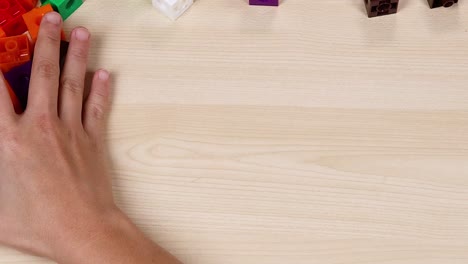 hands move and organize colorful cubes on a light wooden surface, showcasing dexterity and coordination.