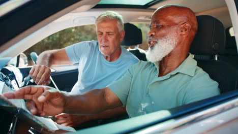 senior male friends in car with map arguing about directions on day trip out