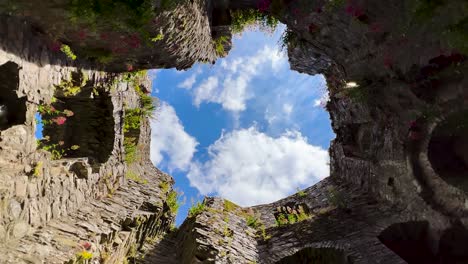 Ein-Blick-Auf-Den-Blauen-Himmel-Mit-Fließenden-Wolken-Von-Unten-Bis-Oben-Auf-Einem-Verlassenen-Alten,-Schmucken-Burgturm,-Irland