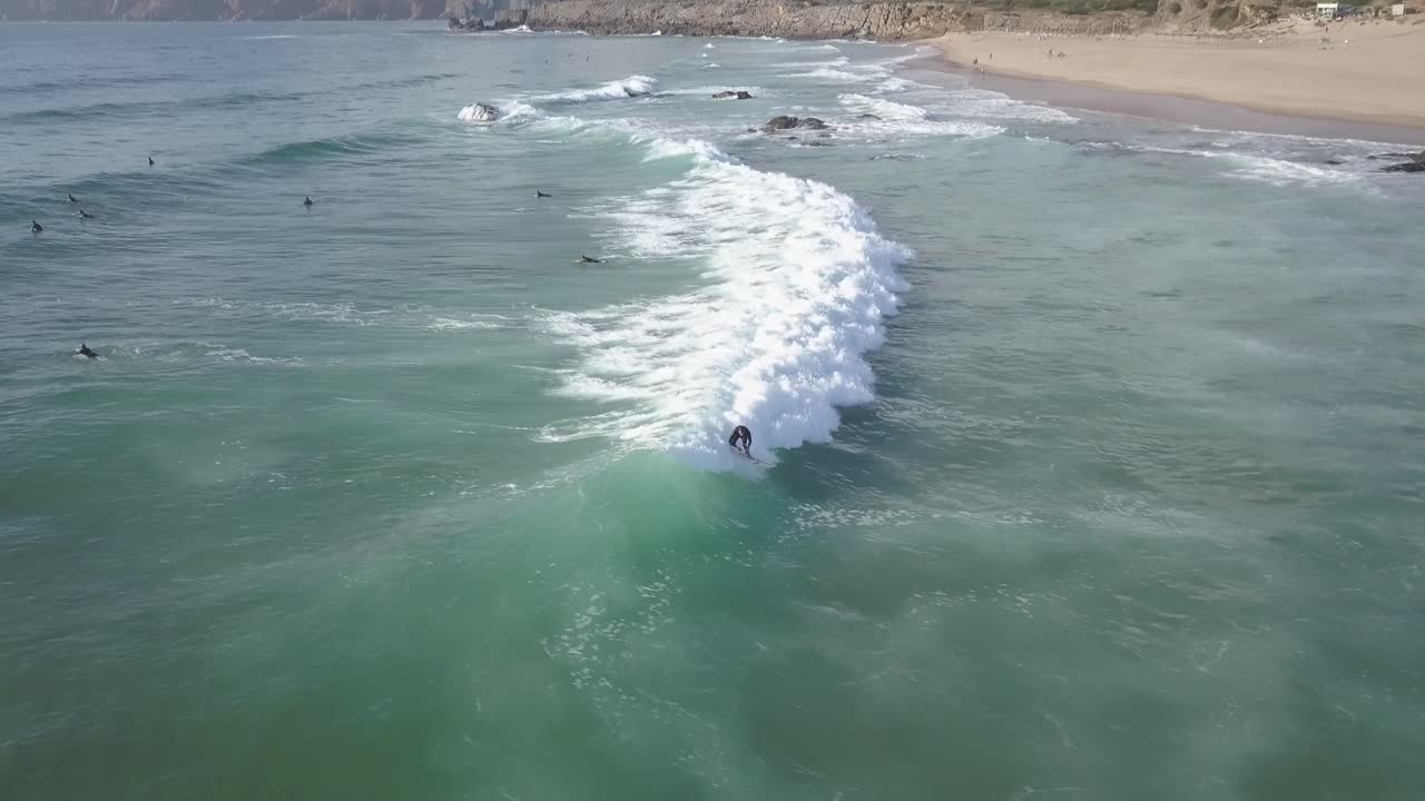 Ripresa aerea panoramica con drone che segue i surfisti sulle onde dell'Oceano Atlantico, in una serata di sole, sulla costa di Cascais, in Portogallo