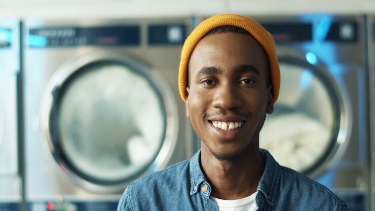 Close Up Of Blurred Cheerful Young Man Smiling To Camera In Laundry Service Room