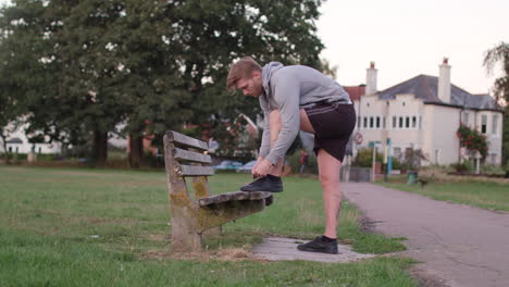 Young-Attractive-Man-Tying-His-Shoes-on-a-Bench-Before-He-Sets-of-For-a-Run,-In-Slow-Motion