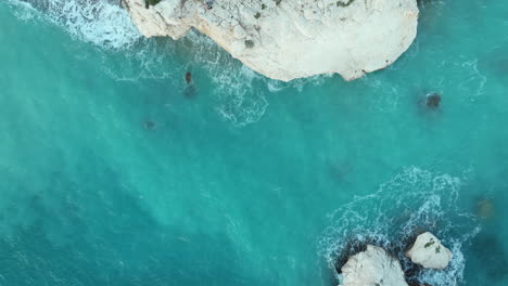 Rock-of-Aphrodite-surrounded-by-turquoise-water-in-aerial-top-down-view,-Cyprus