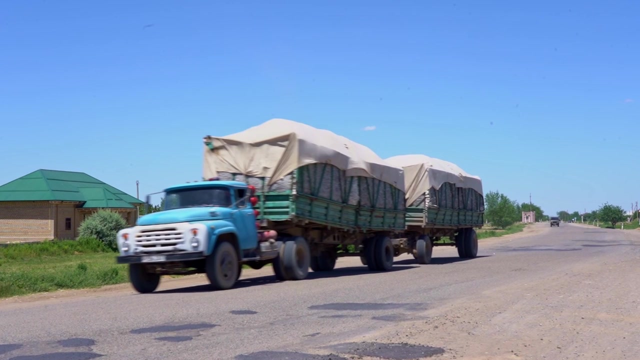 Truck driving along rural road in countryside environment.