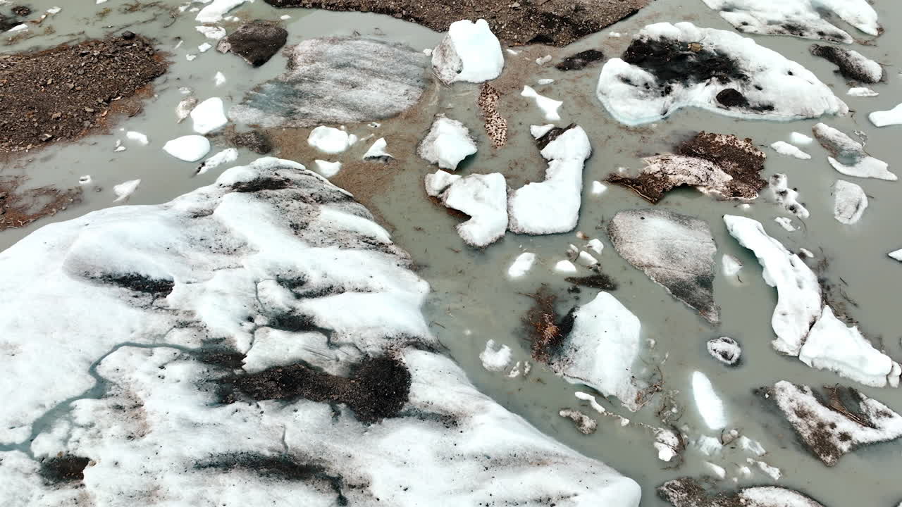 Abstract Pattern of Glacial Ice Chunks in Milky Water. An abstract overhead perspective focuses on various shapes and sizes of glacial ice chunks and sediment floating in milky