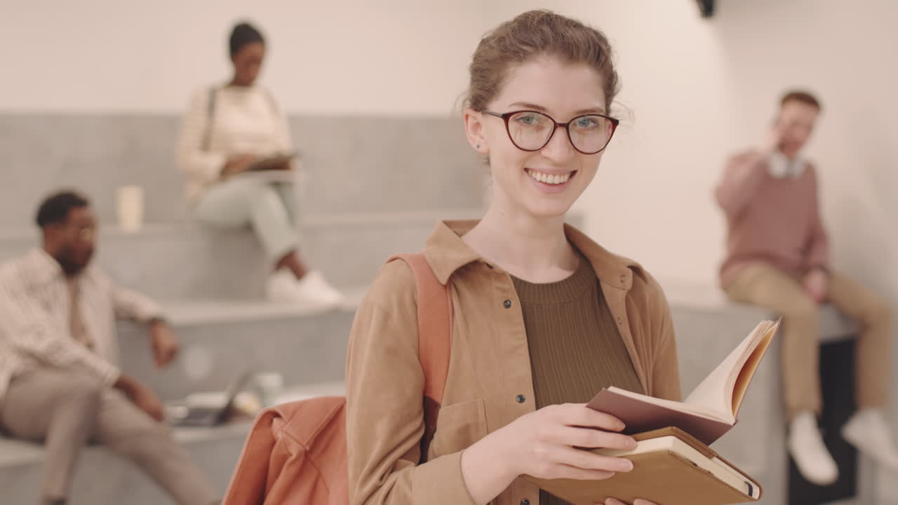 Studentessa sorridente con gli occhiali in posa per la fotocamera