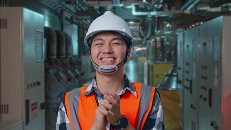 Close Up Of Asian Male Engineer With Safety Helmet Smiling And Clapping His Hands While Standing In Engine Control Room, Work Of Electrical Generators
