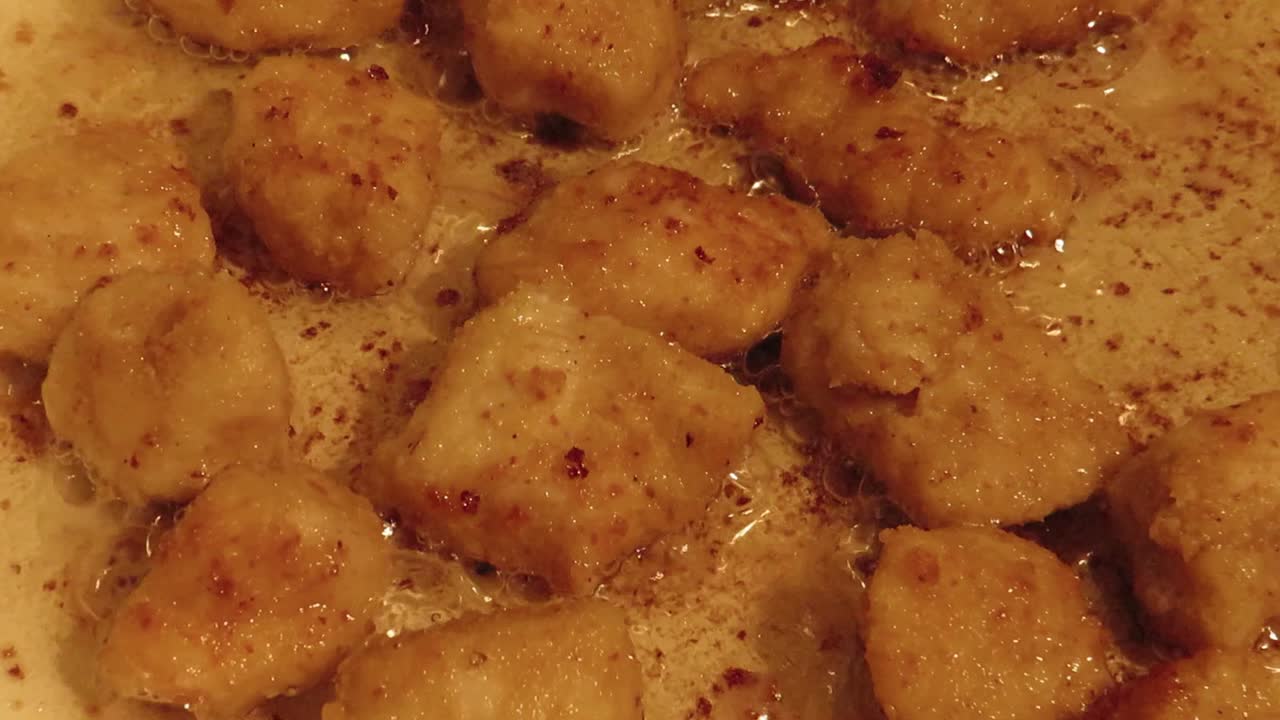 Zoom in into chicken bits being fried for preparation of a recipe