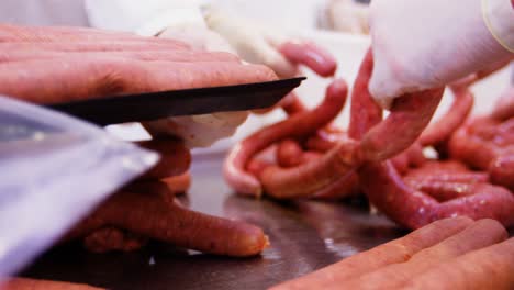 butchers packing sausages in container