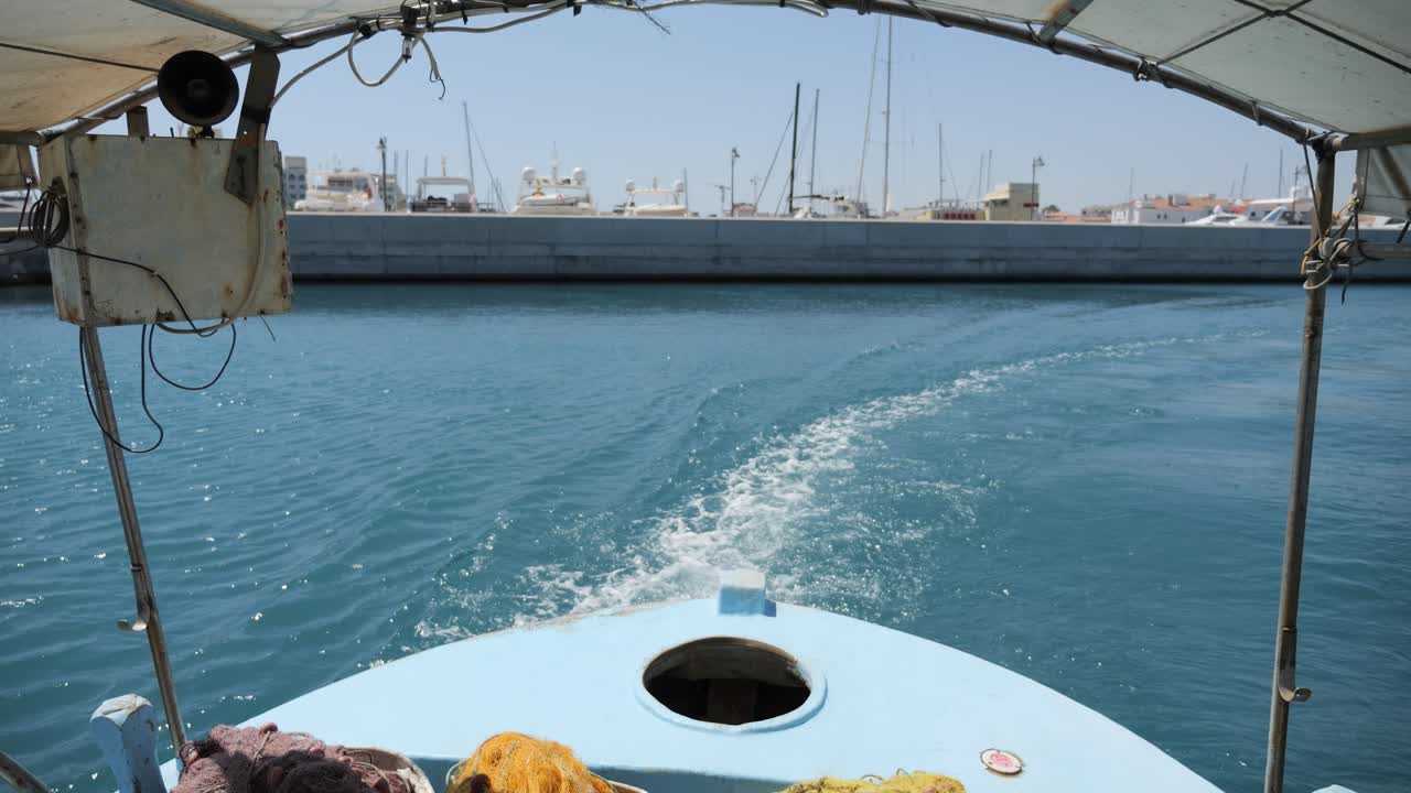 vista desde la popa de un pequeño barco pesquero que sale del puerto en el mar mediterráneo
