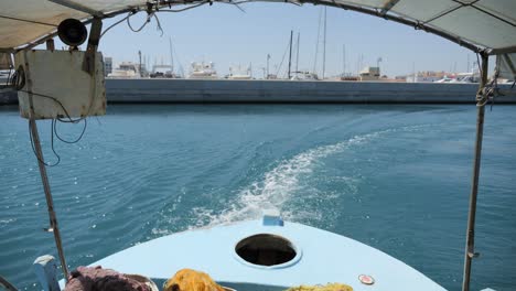 vista desde la popa de un pequeño barco pesquero que sale del puerto en el mar mediterráneo