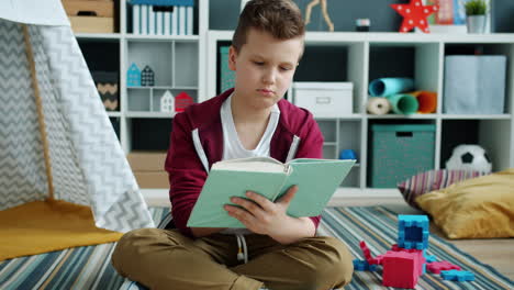 boy reading a book on the floor in a playroom